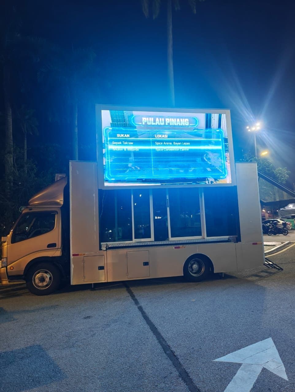 LED truck at night showing a Pulau Pinang event schedule on its screen