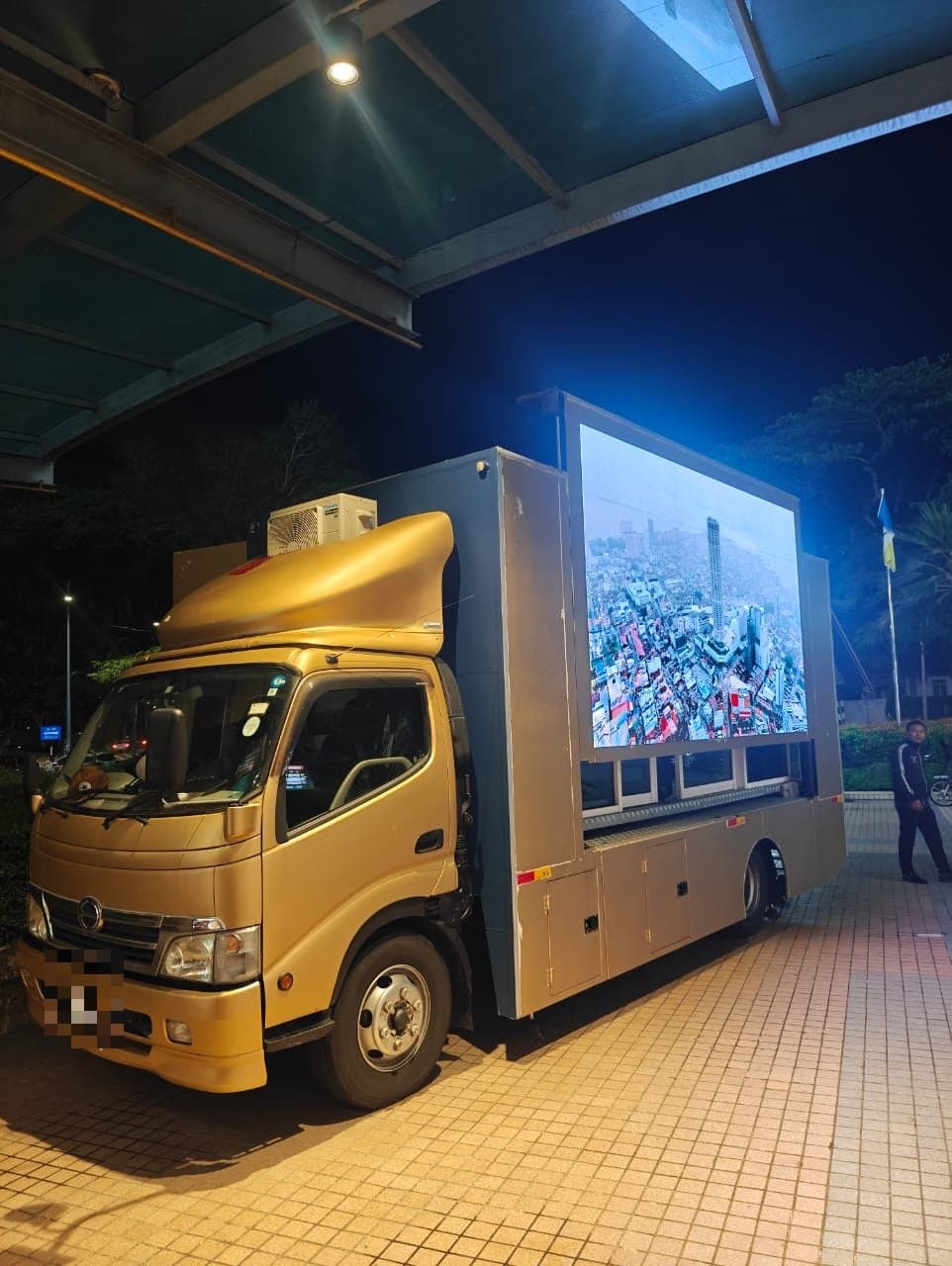 LED truck parked under a canopy at night, its screen on